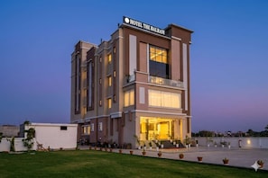A multi-story hotel with a prominent entrance and a balcony. - Hotel The Balram (Ayodhya)