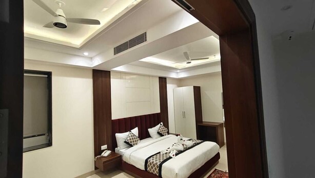 Ein modernes Hotelzimmer mit einem großen Bett, einem Kleiderschrank, einem Nachttisch und einem Deckenventilator.