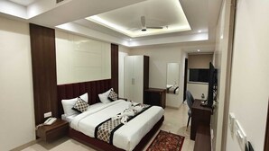 Ein modernes Hotelzimmer mit einem großen Bett, einem Schreibtisch, einem Stuhl und einem Kleiderschrank.