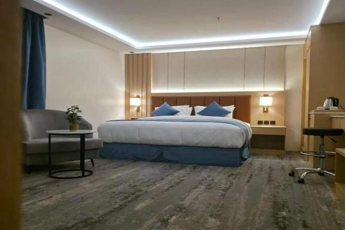 A hotel room with a bed, a chair, a small table, and a desk.