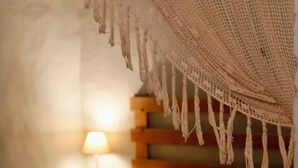 A bed with a headboard, a bedside lamp, and a hanging net. - Casa Rural Mas Garganta (La Vall d'en Bas)