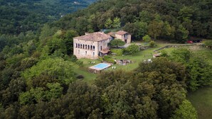 A large, historic stone building with multiple rooms and a swimming pool, surrounded by dense forest. - Casa Rural Mas Garganta (La Vall d'en Bas)