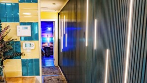 Un pasillo con piso de madera, un tapete, una pared con líneas verticales e iluminación empotrada en el techo.