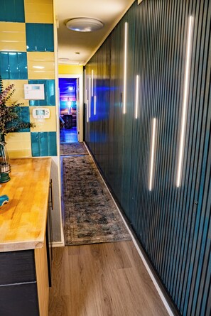 A hallway with a wooden floor, a rug, a wall with vertical lines, and a ceiling with recessed lighting. - Lovely 2-bedroom home - Central Location in Dallas (Dallas)