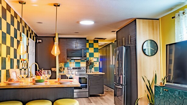 Una cocina moderna con una isla central, electrodomésticos de acero inoxidable y un patrón de pared a cuadros.