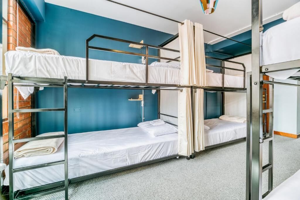 Une chambre avec un lit superposé, un mur bleu, un mur en briques et un sol recouvert de moquette.