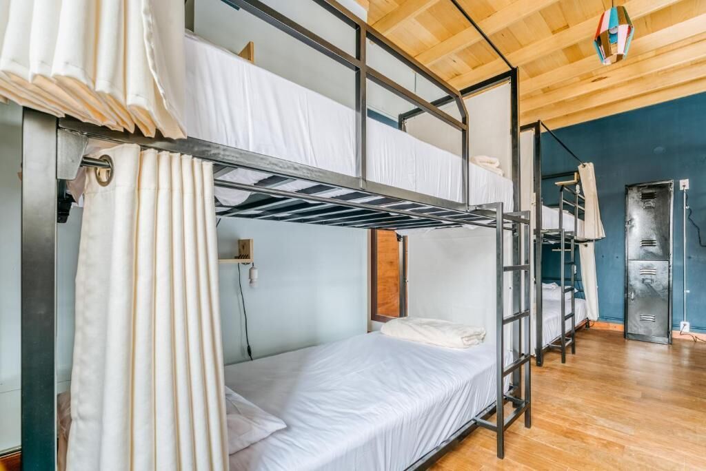 A bunk bed room with a wooden ceiling, a metal ladder, and a curtain.