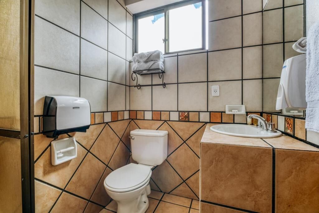 A bathroom with a toilet, sink, and hand dryer.