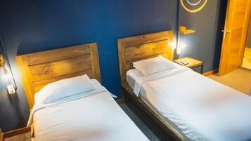 Two single beds with wooden headboards in a room with dark blue walls and a circular wall decoration.