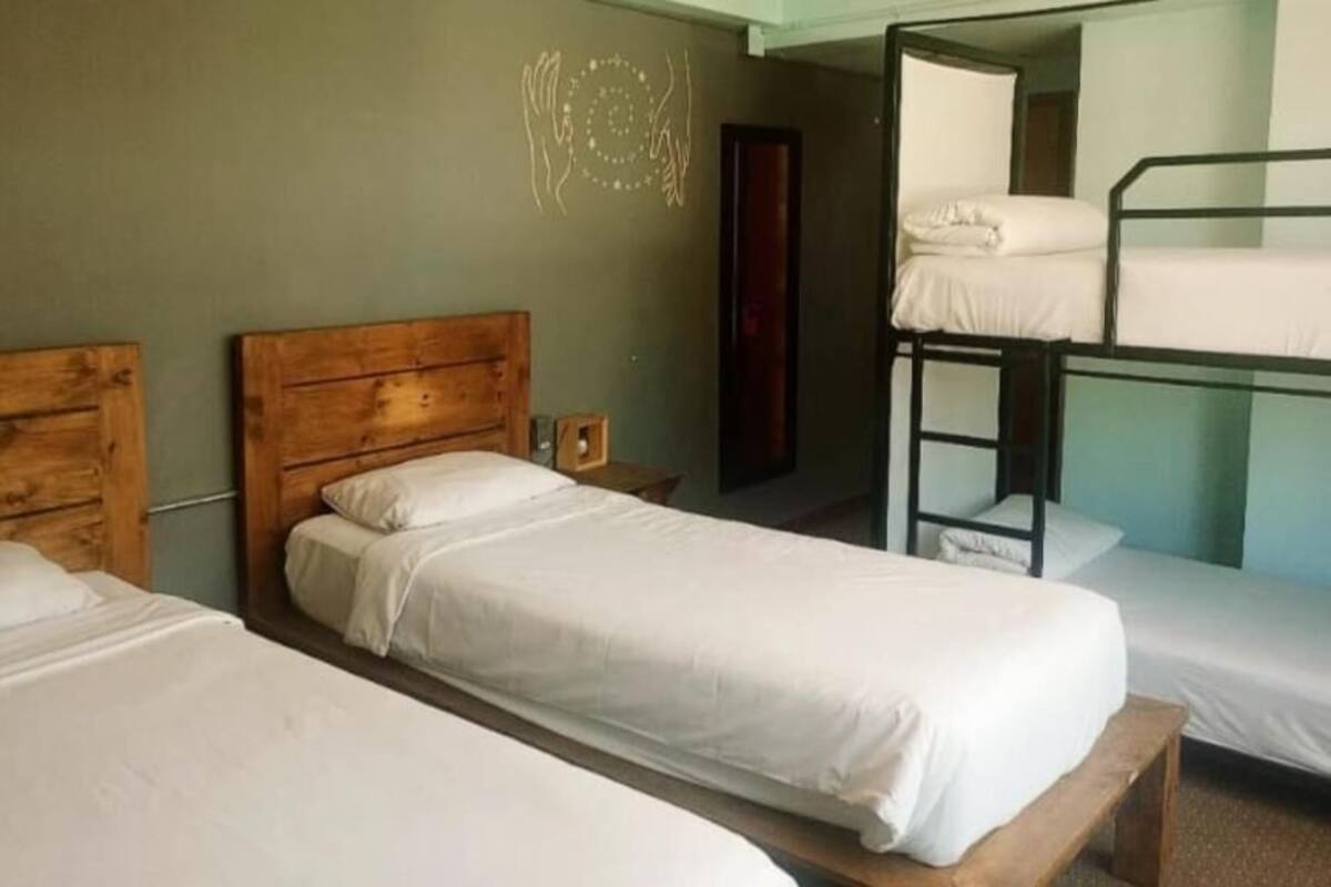 A room with two wooden beds, a bunk bed, and a wall with a decorative symbol.