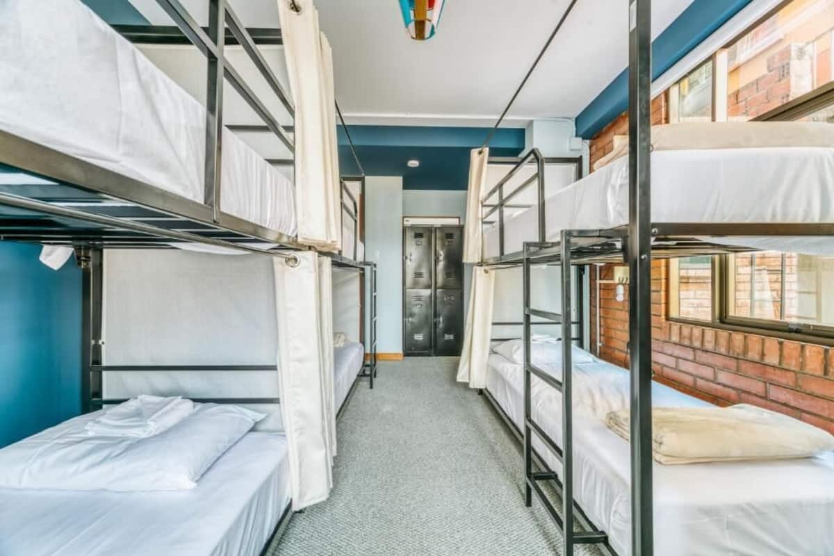 A dormitory room with bunk beds, a door, and a brick wall.