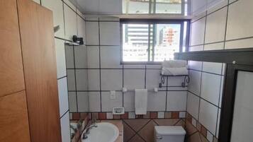 A bathroom with a sink, toilet, and window.