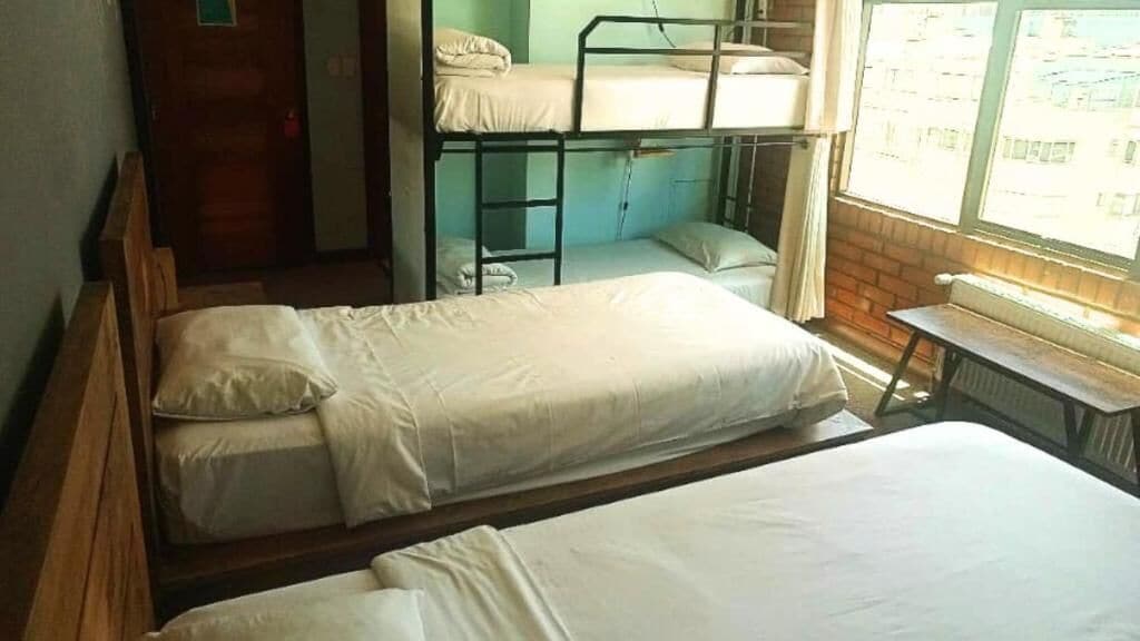 Un dormitorio con literas, un cabecero de madera, una ventana con vistas y un radiador.