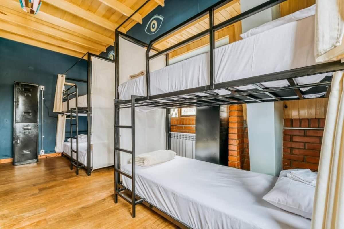 A bunk bed room with a wooden ceiling, a radiator, and a brick wall.