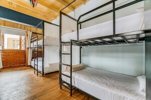 Habitación con literas, techo de madera, pared de ladrillo y una ventana.