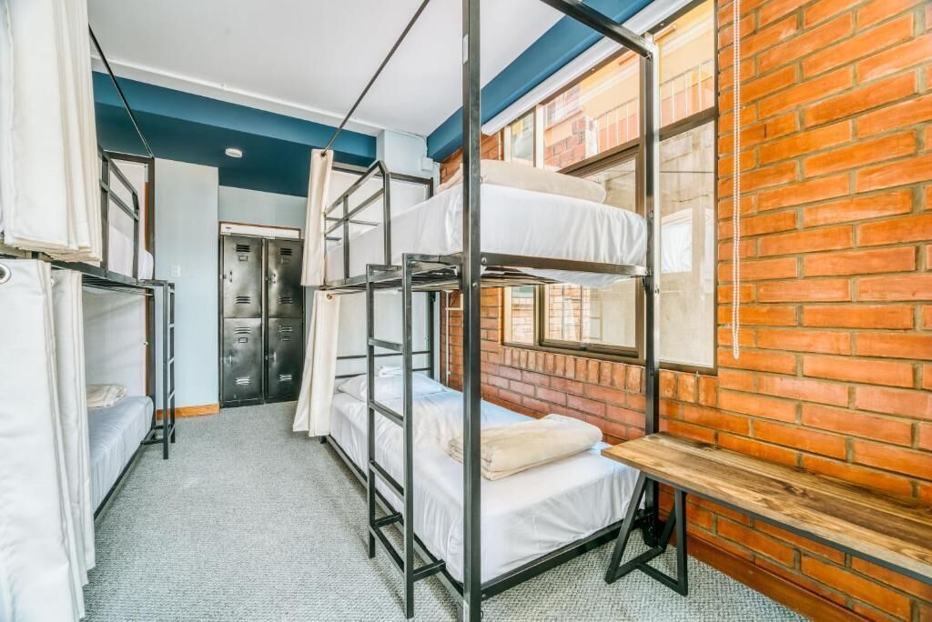 Un dormitorio con literas, una pared de ladrillo, una ventana y una puerta.