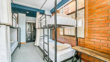 Un dormitorio con literas, una pared de ladrillo, una ventana y una puerta.
