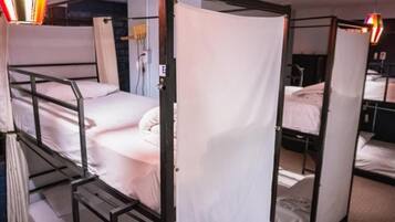 A room with bunk beds, a curtain, and a small table.