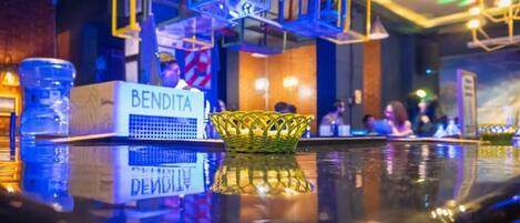 Un área de bar con una botella de agua, un letrero que dice 'BENDITA' y una cesta tejida.