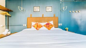 Habitación de hotel con cama, dos lámparas de pared y dos cuadros enmarcados.