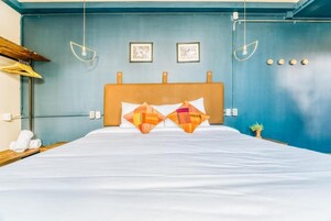 Habitación de hotel con cama, dos lámparas de pared y dos cuadros enmarcados.