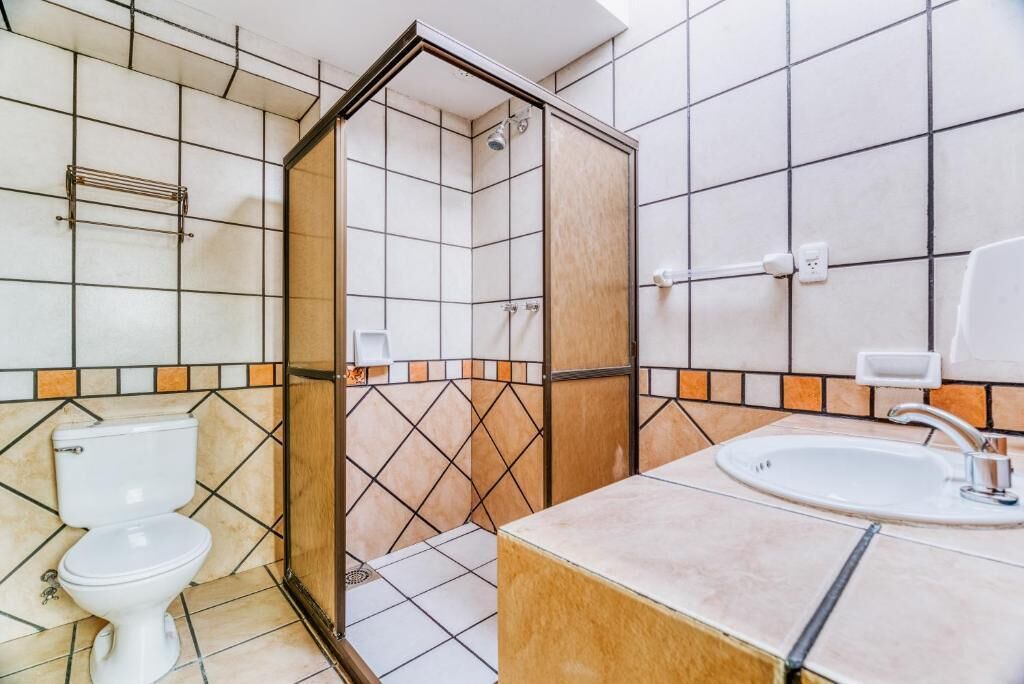 Et badeværelse med bruser, toilet og håndvask.