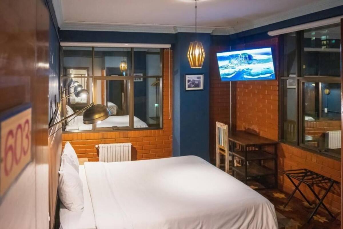 A hotel room with a bed, a desk, a chair, a TV, and a window.