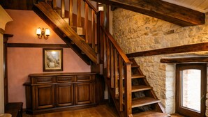 A wooden staircase with a stone wall, a wooden cabinet, and a framed picture on the wall.