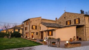 A traditional stone building with multiple windows and a gravel driveway.