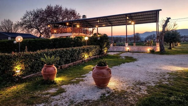 A covered outdoor area with a pergola, decorative lighting, and two large terracotta pots.