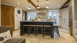 A kitchen with a central island, wooden stools, and a refrigerator. - Beckside, Kettlewell, Yorkshire Dales (Kettlewell, Skipton)