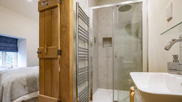 A modern bathroom with a glass-enclosed shower, a wooden door, and a white sink. - Beckside, Kettlewell, Yorkshire Dales (Kettlewell, Skipton)
