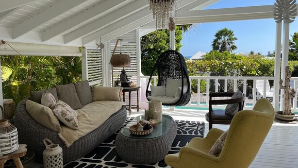 A covered outdoor seating area with a sofa, chairs, and a hanging chair. - Tropical villa - Orient Bay Park (Saint-Martin)