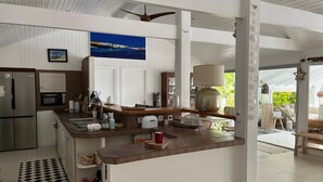 A modern kitchen with a large island, stainless steel appliances, and a view to the outdoor patio area. - Tropical villa - Orient Bay Park (Saint-Martin)