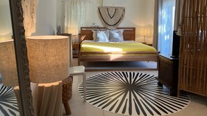 A modern bedroom with a bed, bedside lamps, a decorative wall piece, and a wooden wardrobe. - Tropical villa - Orient Bay Park (Saint-Martin)