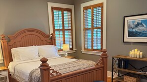 Une chambre à coucher avec un lit en bois, un banc, un tapis et une bibliothèque.