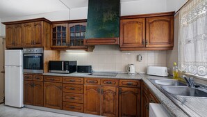 A kitchen with wooden cabinets, a refrigerator, an oven, a microwave, a toaster, and a sink. - Villa Martins with Private Pool, Wi-Fi, and Air Conditioning (Albufeira)
