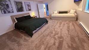 Een slaapkamer met een bed, een slaapbank, een plafondventilator en een televisie aan de muur.