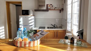 A kitchen with a refrigerator, microwave, sink, and a window. There is a basket of bread and water bottles on the counter. - L'Echappée Urbaine Rouennaise - Hyper downtown - Rouen Left Bank Station (Rouen)