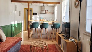 A compact living space with a kitchen area, a dining table with chairs, a television, and a small seating area with a sofa and a chair. - L'Echappée Urbaine Rouennaise - Hyper downtown - Rouen Left Bank Station (Rouen)