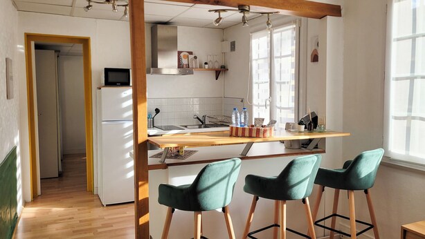A compact kitchen with a wooden bar counter, two bar stools, and a refrigerator. - L'Echappée Urbaine Rouennaise - Hyper downtown - Rouen Left Bank Station (Rouen)