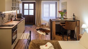 Une chambre d’hôtel compacte comprenant un coin cuisine, un espace repas, un lit et un tapis en peau de vache.