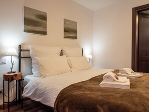 A hotel room with a bed, two wall-mounted lamps, a wooden nightstand, and a door. - Cjase Longobarde (Cividale del Friuli)