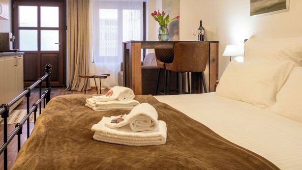 Une chambre d’hôtel avec un lit, un bureau, une chaise, une petite table et une fenêtre avec des rideaux.