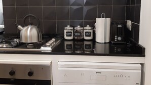 Ett kök med en vattenkokare, salt, socker och kaffeburkar på bänkskivan.