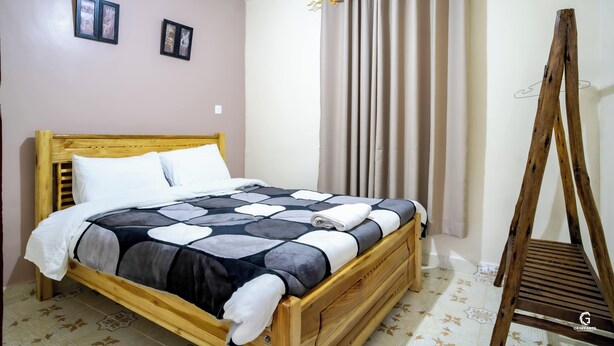 A wooden bed with a patterned bedspread, a wooden headboard, and a wooden chair.