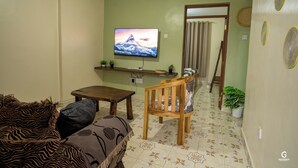 A living room with a television, a sofa, a wooden table, and a chair.