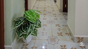 A narrow hallway with patterned floor tiles, a white sink, and a potted plant.