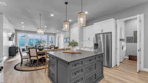 Una cocina moderna con una isla central, electrodomésticos de acero inoxidable e iluminación colgante.