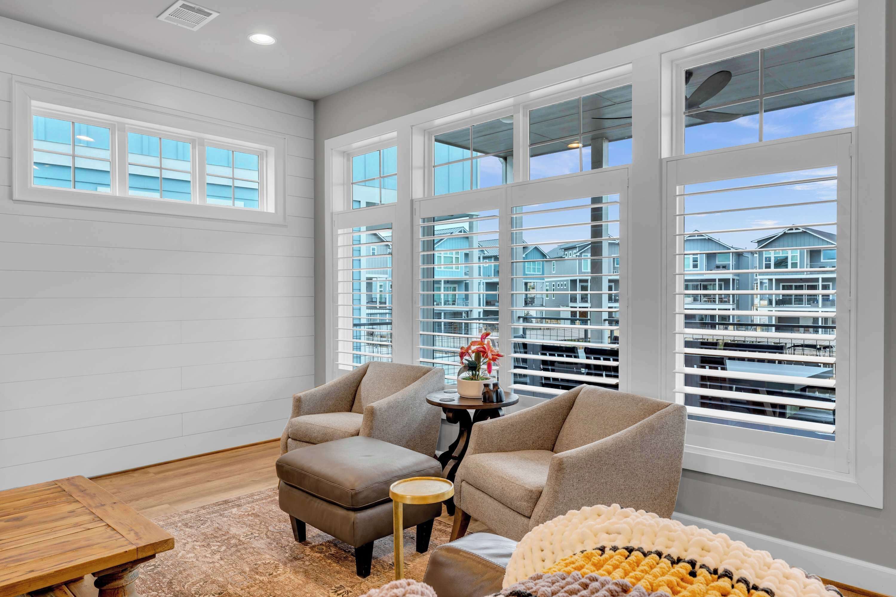 A modern living room with large windows, a sofa, a coffee table, and a rug.